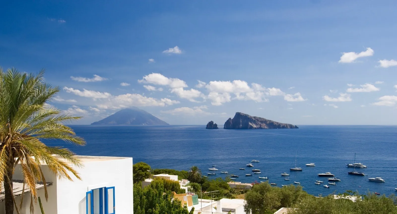 White house and palm above Panarea's bay with the islets offshore