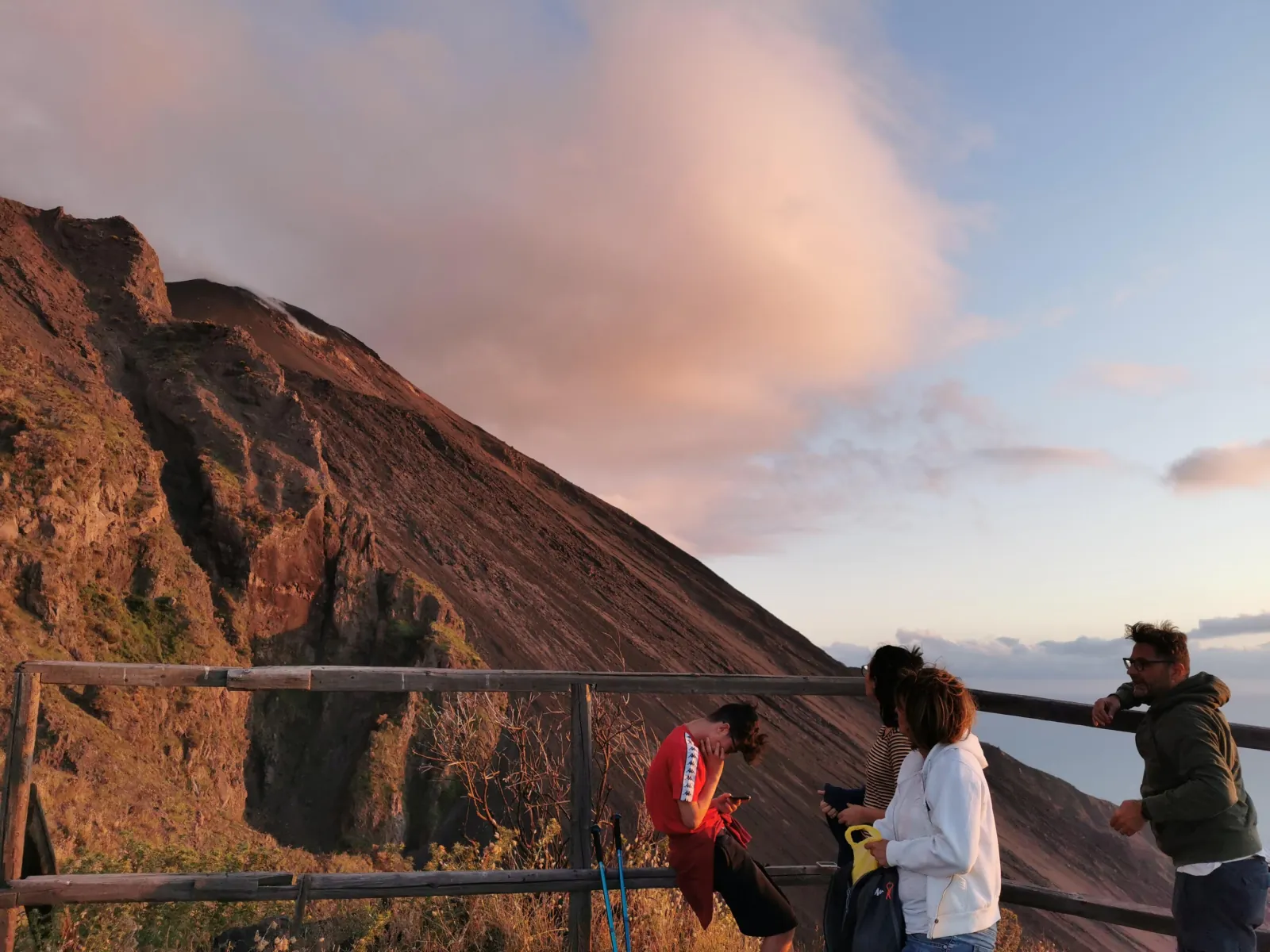 Hikers at the railing above the Sciara del Fuoco at sunset