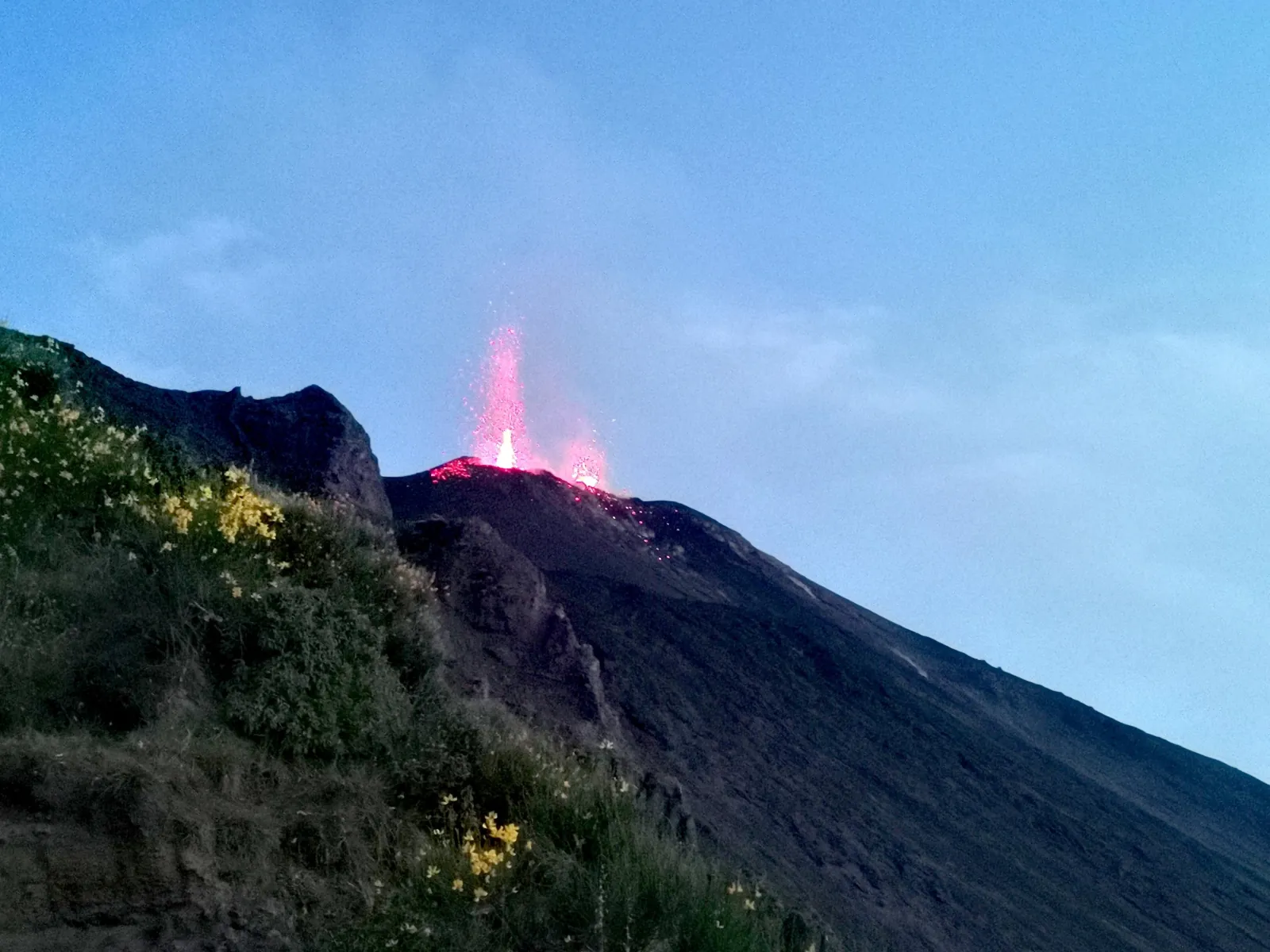 Small eruption above green scrub on the upper slope