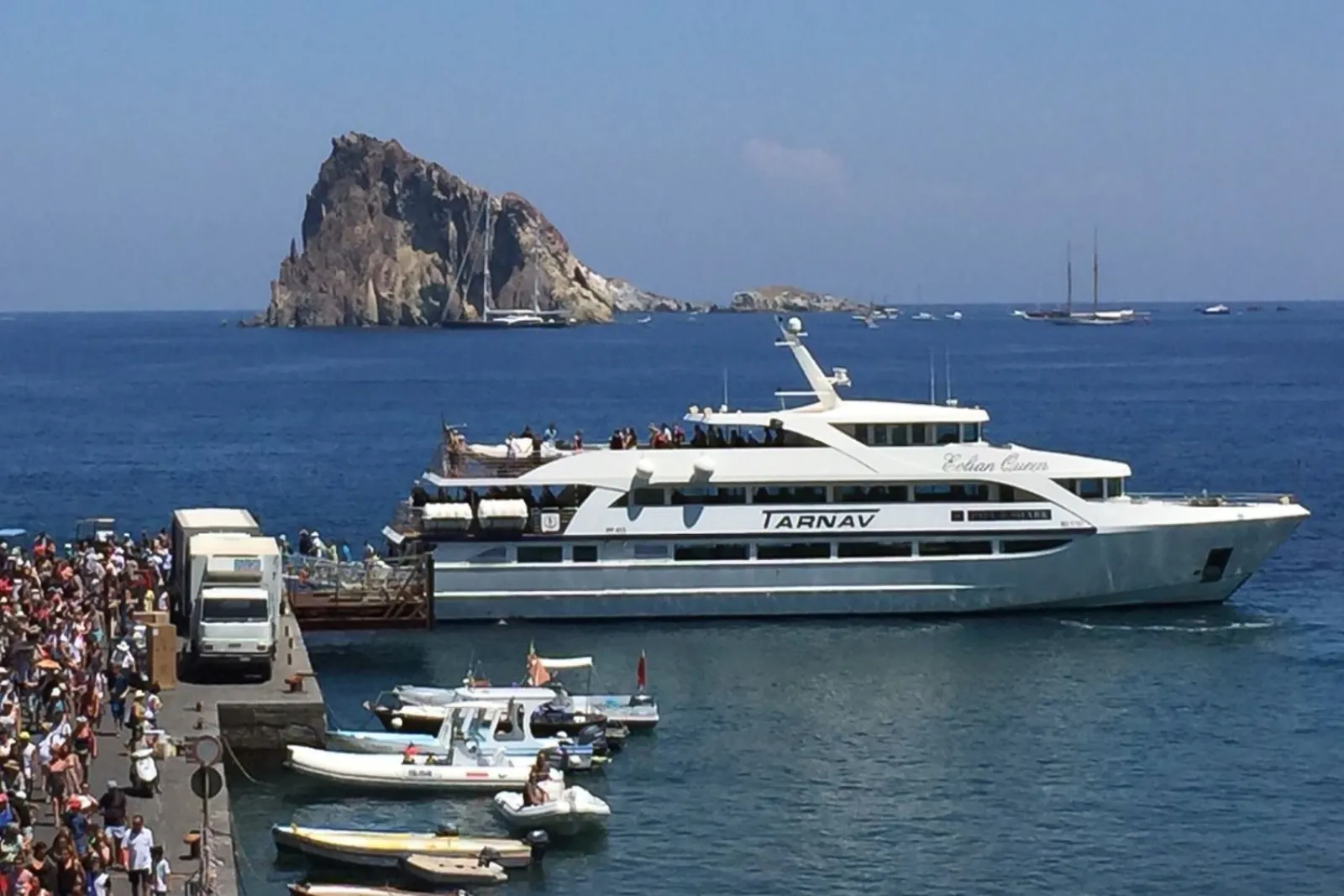Excursion boats at a busy island quay with an islet offshore