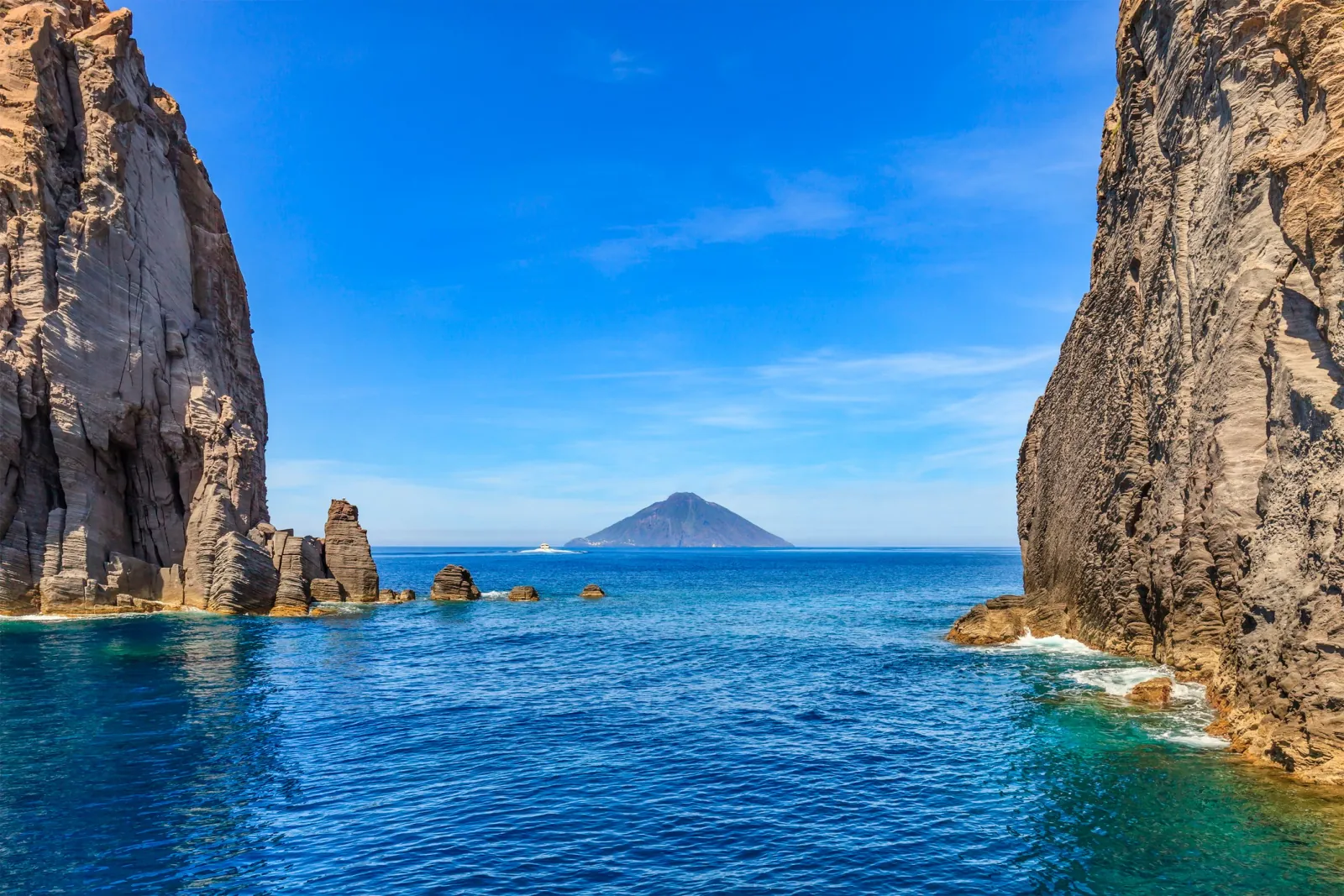 Stromboli on the horizon between two sea cliffs