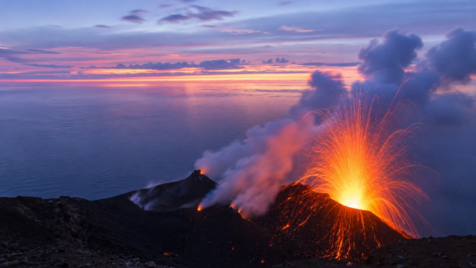Stromboli's crater erupting under a pink evening sky