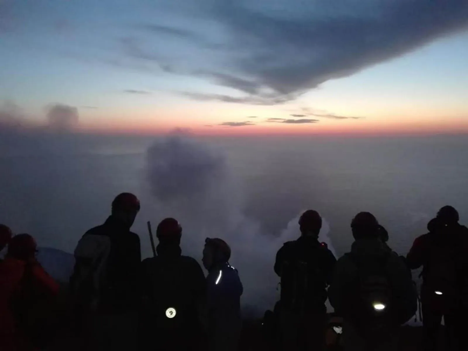 Hikers in silhouette at dusk on the volcano