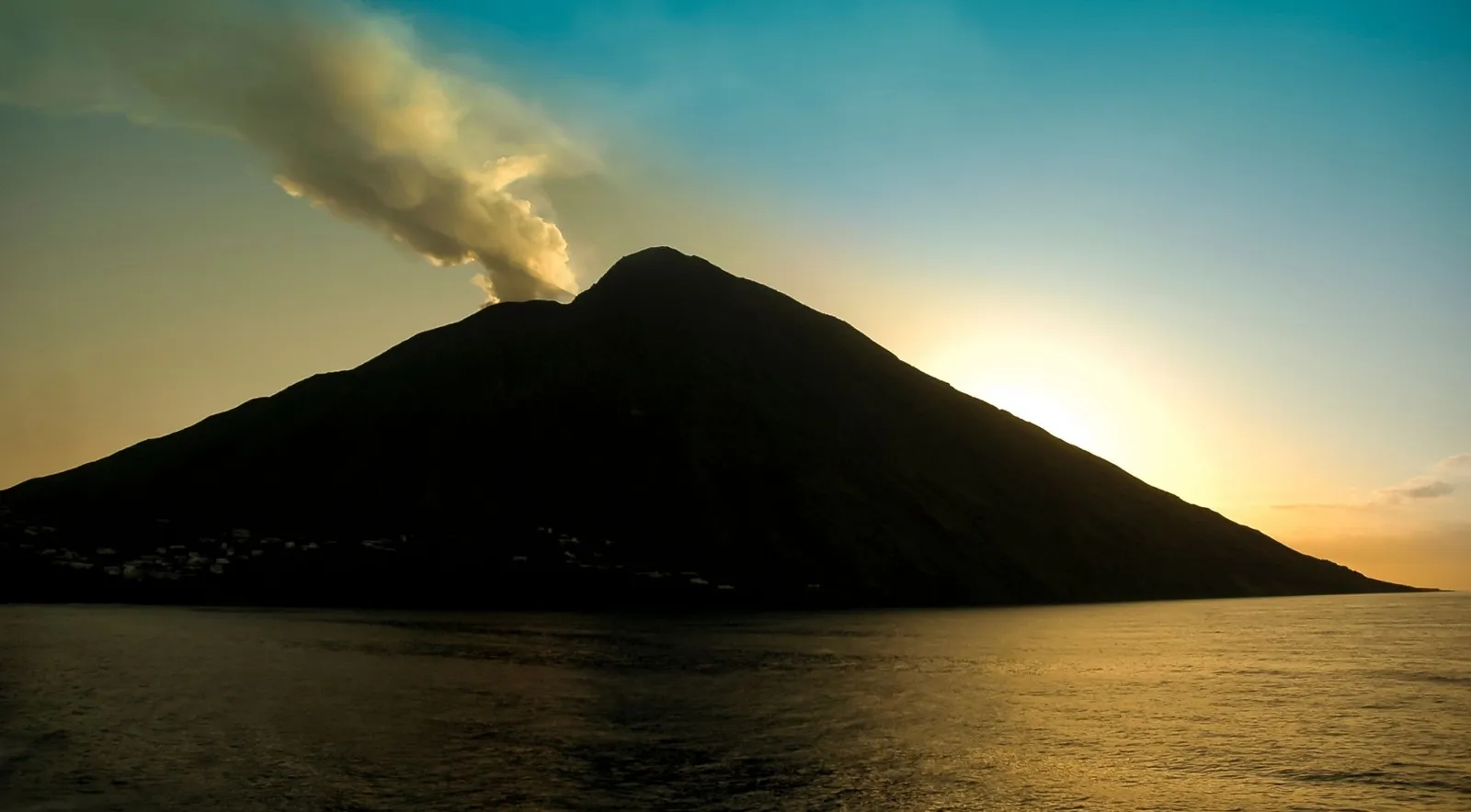 Stromboli in silhouette with its plume at sunset
